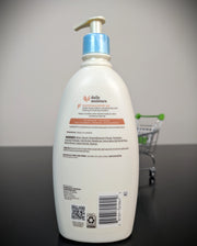 A large white bottle of daily moisture hand cream with a blue pump, shown from the back on a dark surface with a miniature shopping cart prop against a gray background.