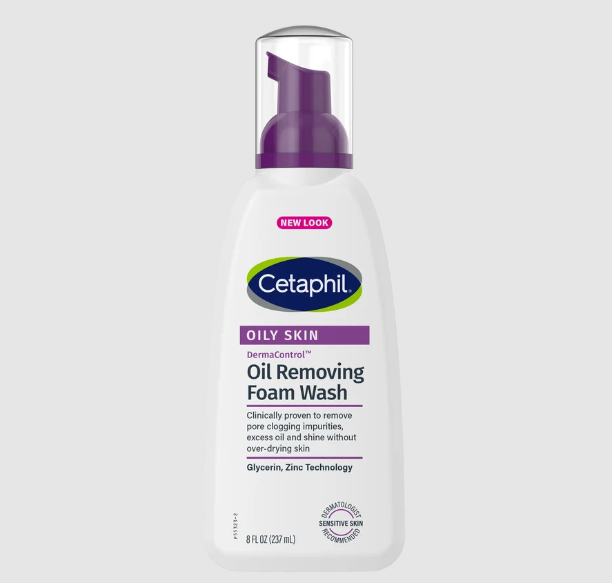 A bottle of Cetaphil Oily Skin Oil Removing Foam Wash on a light gray background. The bottle is white with a purple pump and features the Cetaphil logo in green and blue.